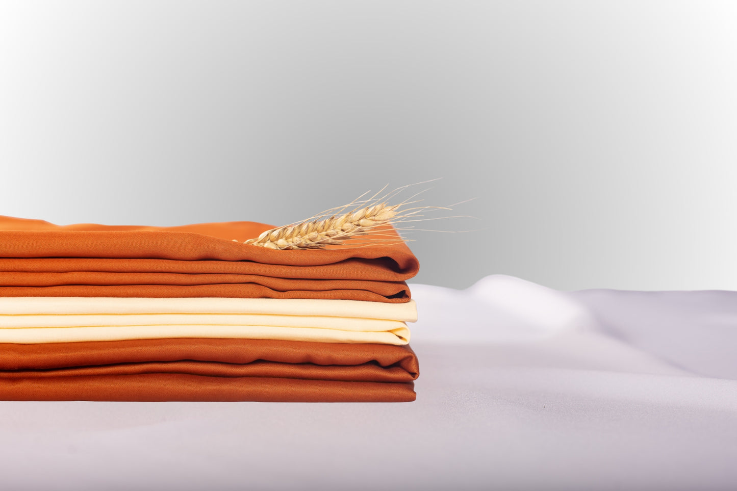 Close-up of cream and terracotta sateen bed linen by Once@Home showing gentle folds and refined finish