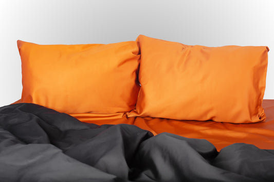 Terracotta and black sateen bed linen by Once@Home with soft pillows and a smooth, elegant drape