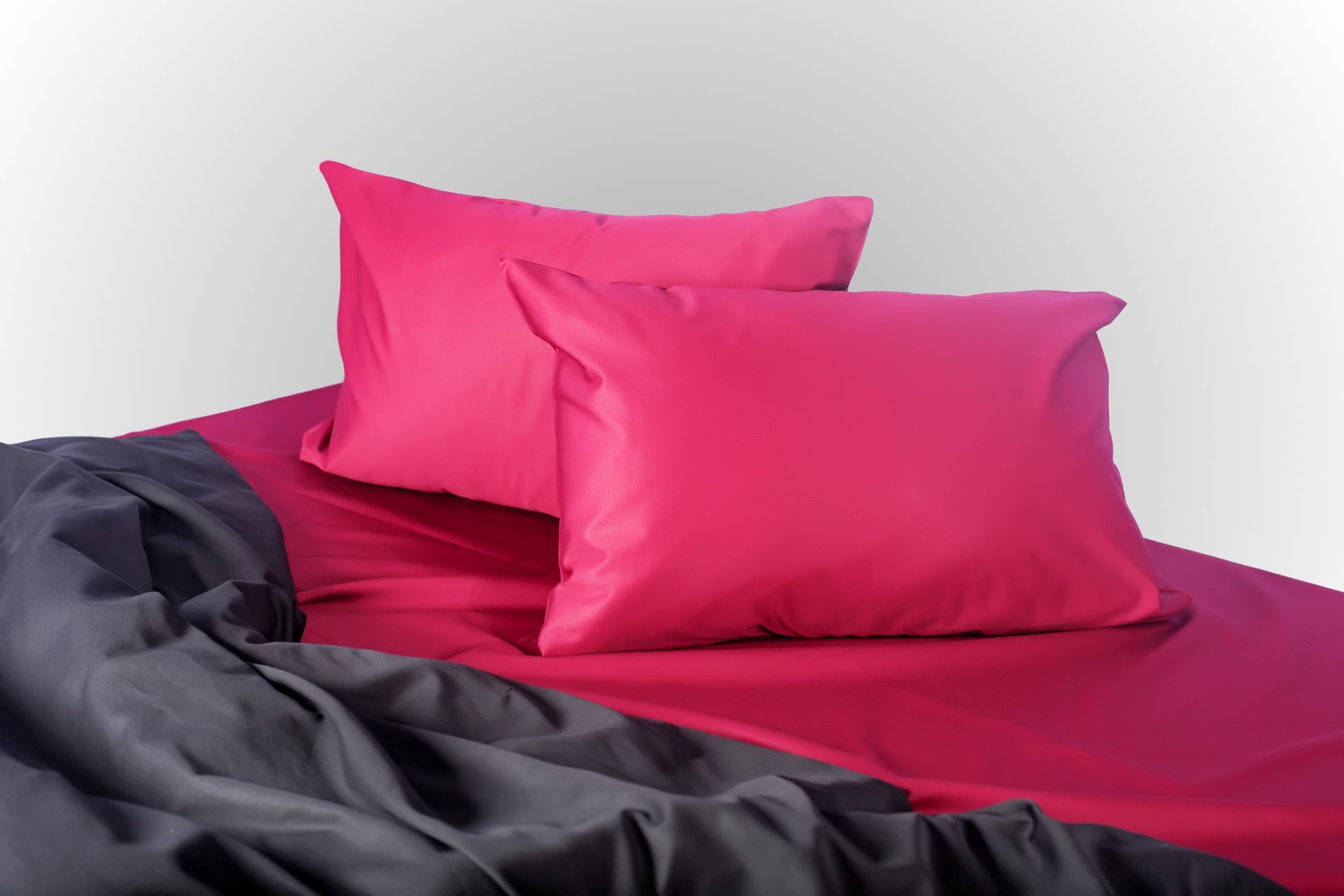 Burgundy and black sateen bed linen by Once@Home with soft pillows and a smooth, elegant drape