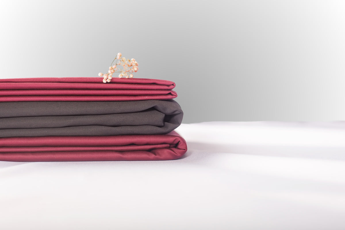 Texture detail of burgundy and black sateen bed linen by Once@Home with subtle sheen and soft touch