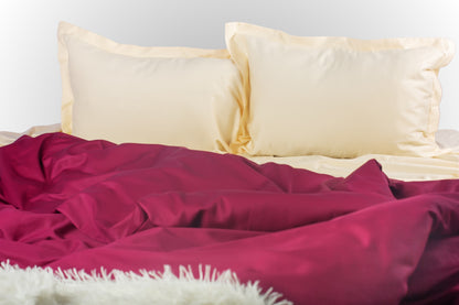Cream and burgundy sateen bed linen by Once@Home with soft pillows and a smooth, elegant drape