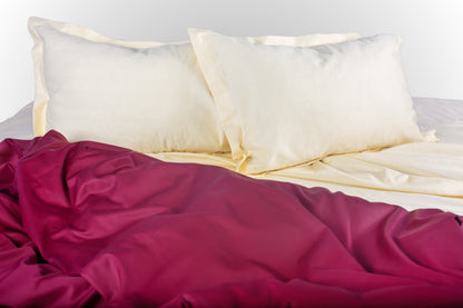 Styled cream and burgundy sateen bed linen by Once@Home creating a warm and refined bedroom atmosphere