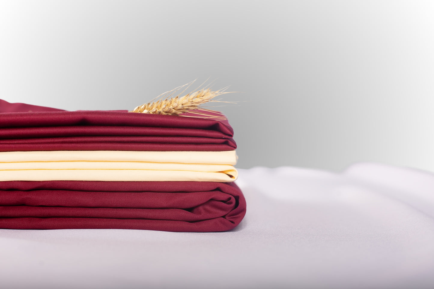 Texture detail of cream and burgundy sateen bed linen by Once@Home with subtle sheen and soft touch