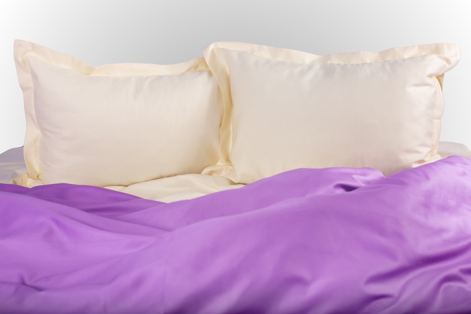 Cream and purple sateen bed linen by Once@Home with soft pillows and a smooth, elegant drape