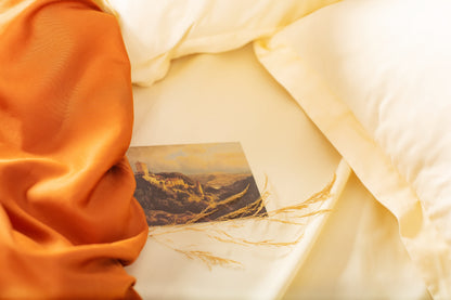 Close-up of cream-terracotta sateen bed linen by Once@Home showing gentle folds and refined finish