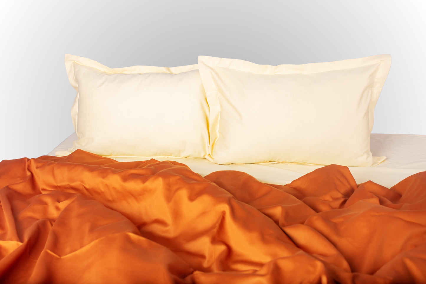 Close-up of cream-terracotta sateen bed linen by Once@Home showing gentle folds and refined finish