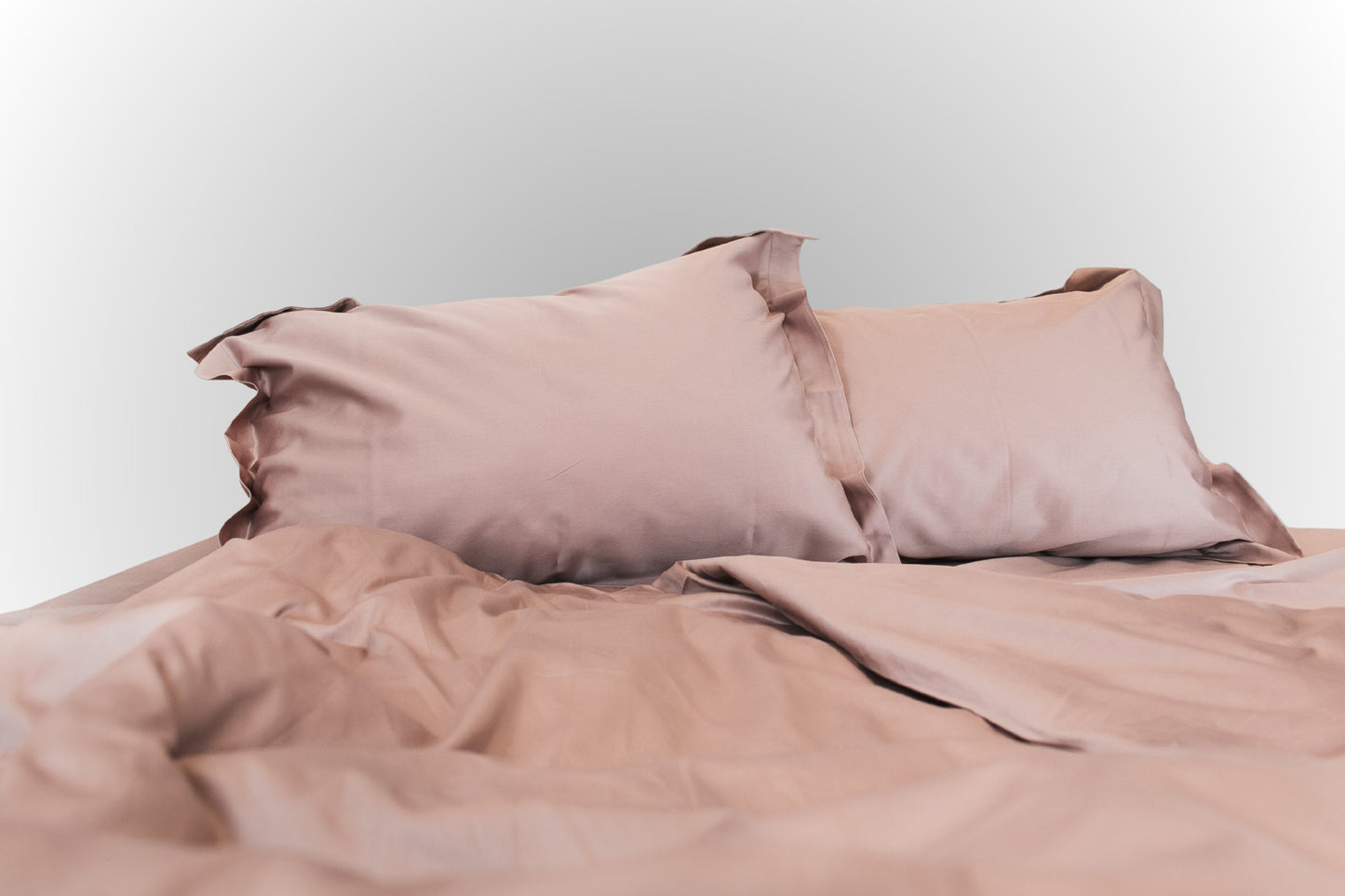 Studio image of pale pink sateen bed linen by Once@Home in a clean, minimalist setting