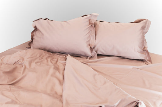 Styled pale pink sateen bed linen by Once@Home arranged in a calm, elegant way