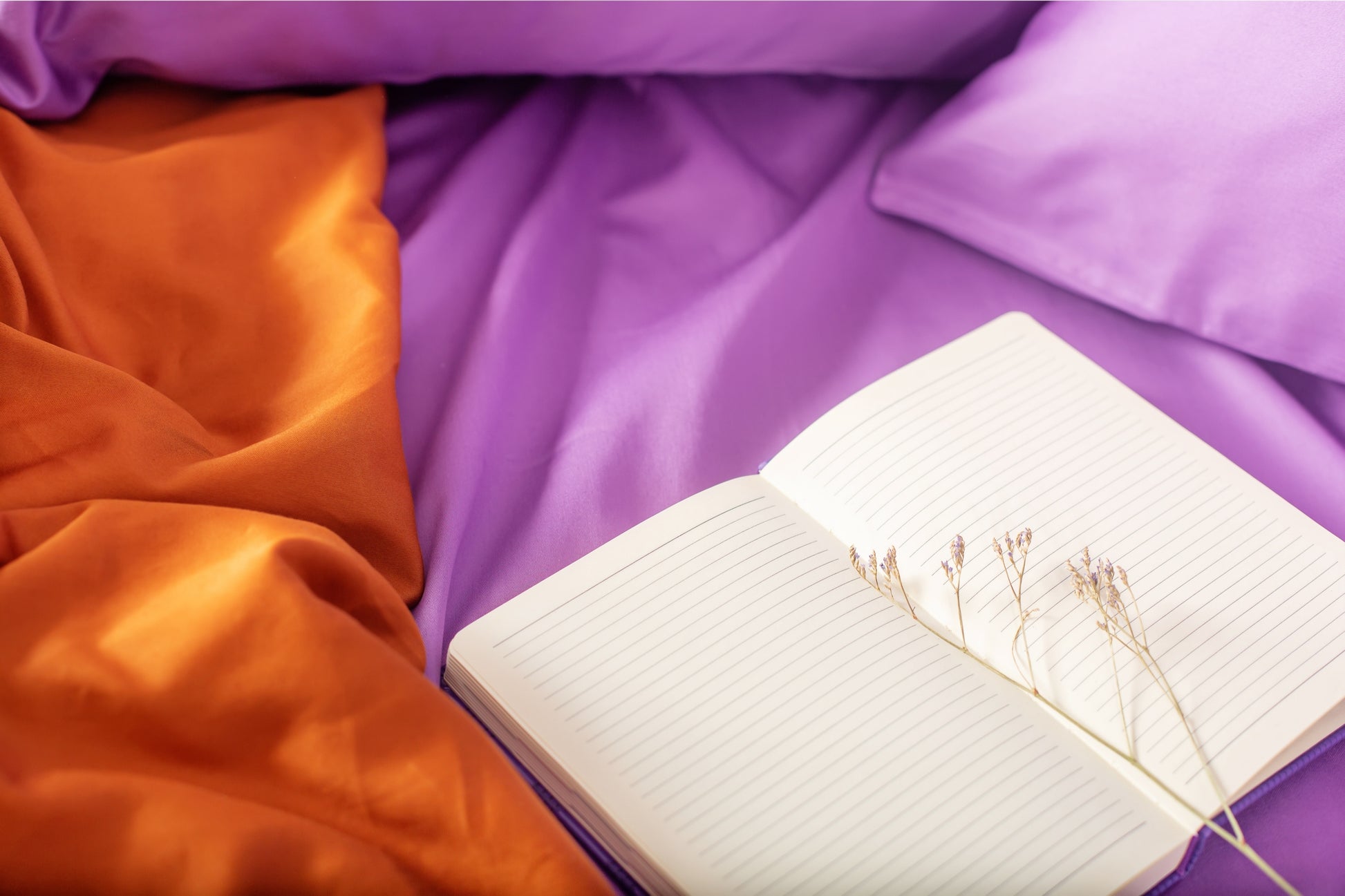 Close-up of purple and terracotta sateen bed linen by Once@Home showing gentle folds and refined finish