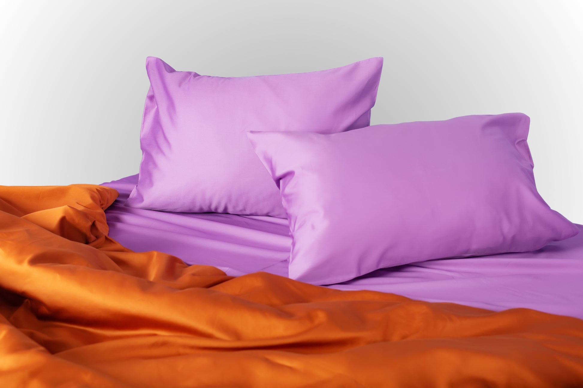 Styled purple and terracotta sateen bed linen by Once@Home creating a warm and expressive bedroom mood