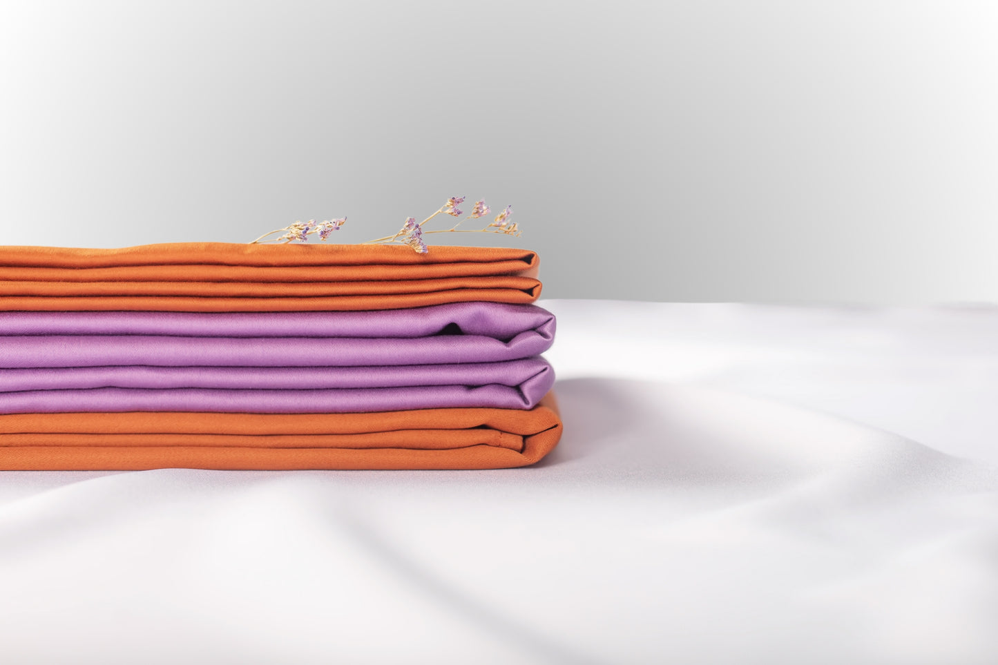 Texture detail of purple and terracotta sateen bed linen by Once@Home with subtle sheen and soft touch