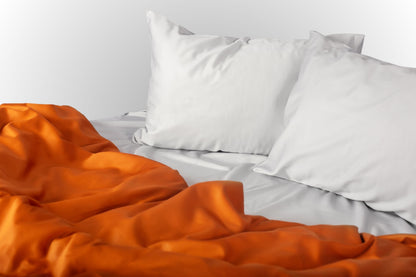 Styled silver and terracotta sateen bed linen by Once@Home creating a warm and balanced bedroom atmosphere