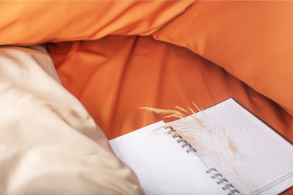 Close-up of terracotta-beige sateen bed linen by Once@Home showing gentle folds and refined finish