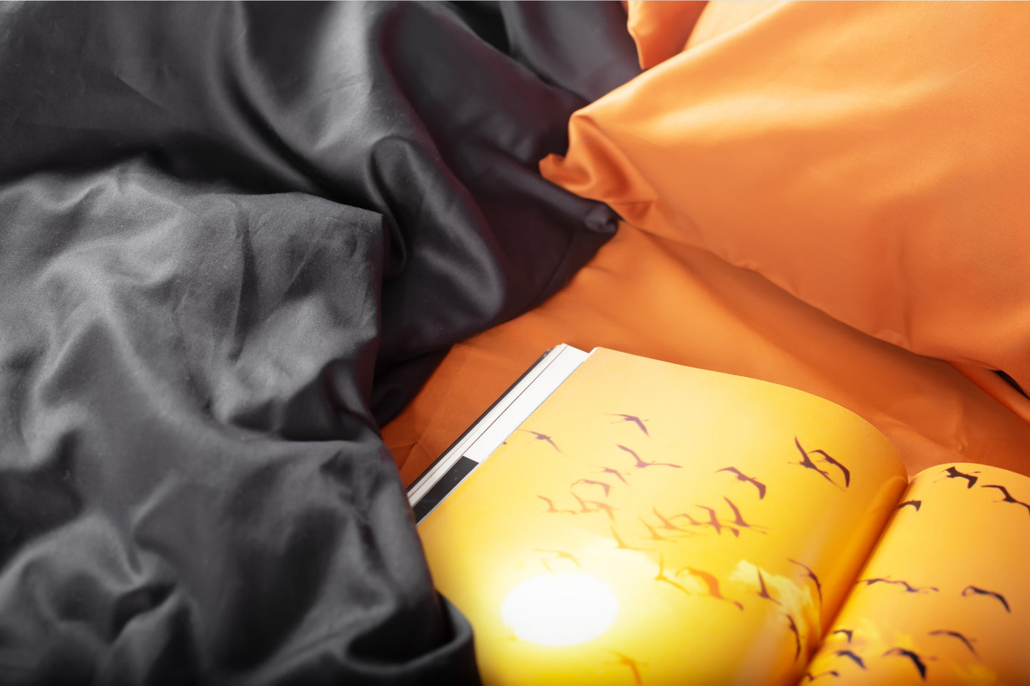 Close-up of terracotta and black sateen bed linen by Once@Home showing gentle folds and refined finish