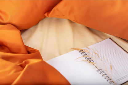 Close-up of terracotta-cream sateen bed linen by Once@Home showing gentle folds and refined finish