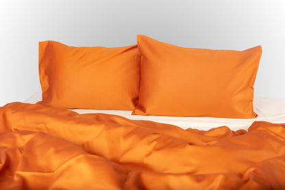 Close-up of terracotta-cream sateen bed linen by Once@Home showing gentle folds and refined finish