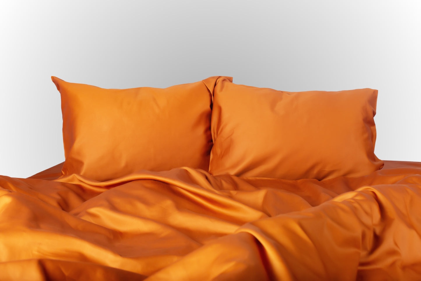 Terracotta sateen bed linen by Once@Home with soft pillows and a smooth, elegant drape