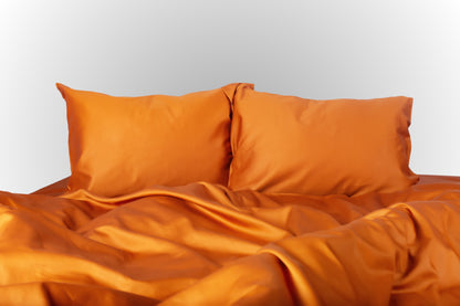 Terracotta sateen bed linen by Once@Home with soft pillows and a smooth, elegant drape
