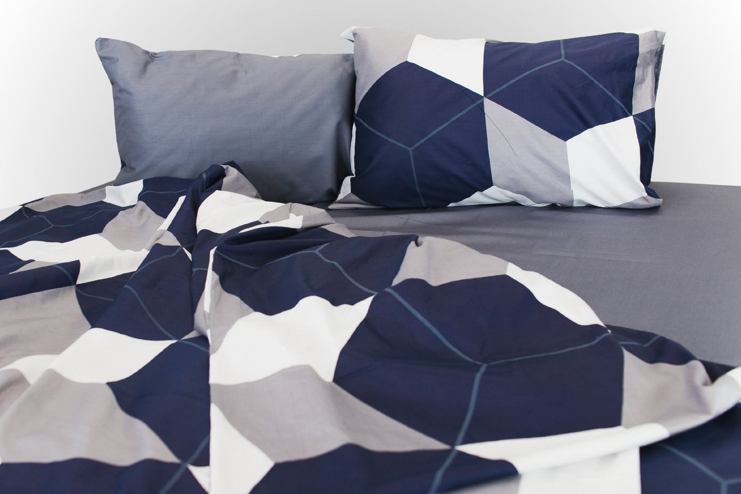Soft folds of geometric sateen bed linen by Once@Home with blue and neutral tones